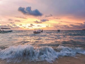 Stunning Cartagena sunset over the sea with boats, waves, and vibrant sky.